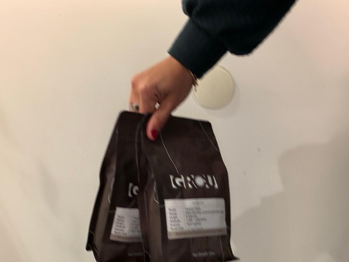Una mano sostiene dos bolsas de café de GROU con su etiqueta