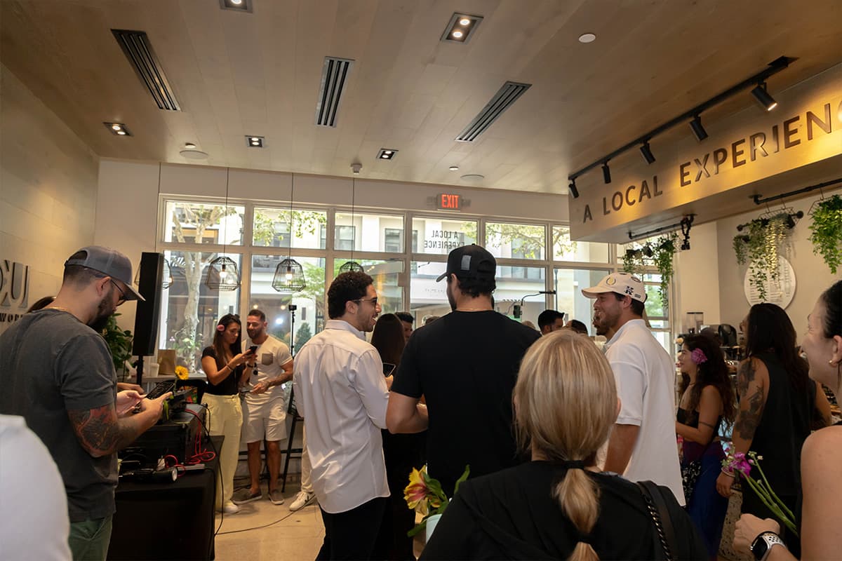 Guests mingling inside GROU during the Coffee Party while a DJ plays from a table near the windows