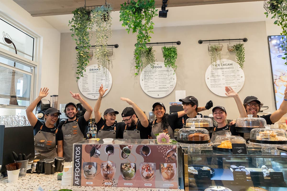 GROU team cheering with arms raised behind the counter, above the affogato display and pastry case