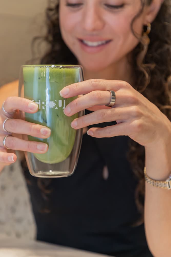 Mujer sonriente sosteniendo un Coconut Sweet Matcha en un vaso de GROU