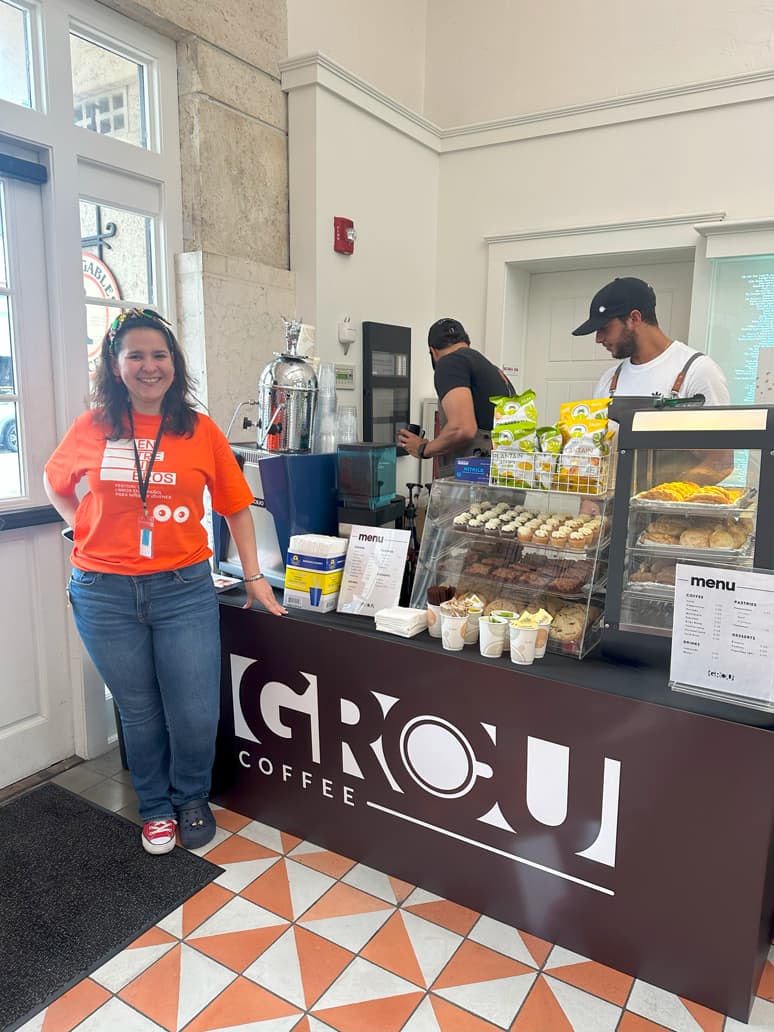 GROU Coffee counter at EntreLibros Fest with pastries and cupcakes on display and a woman in a festival shirt