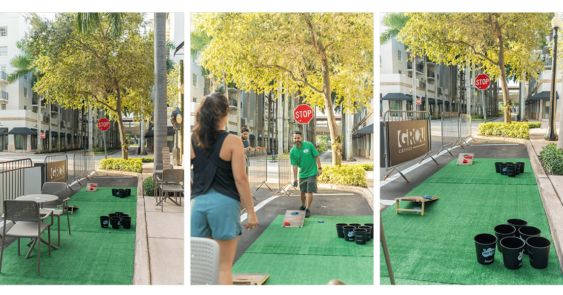 Parking Day frente a GROU: estacionamientos con césped verde, cornhole, juegos de baldes y un jugador lanzando un saquito